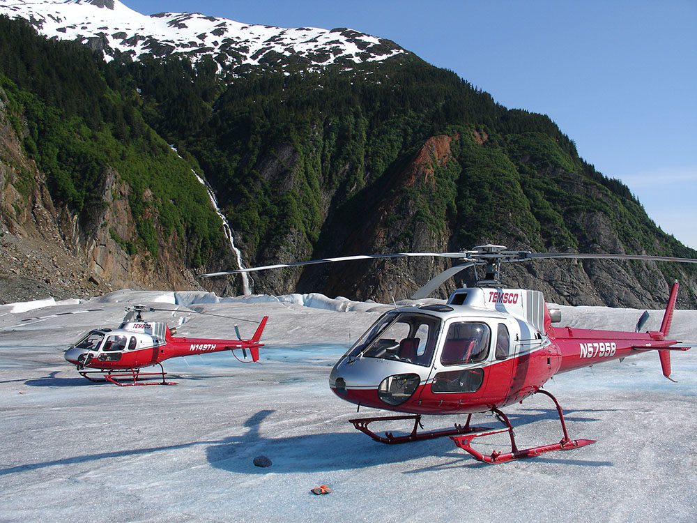 Two red and white helicopters on a snowy surface
