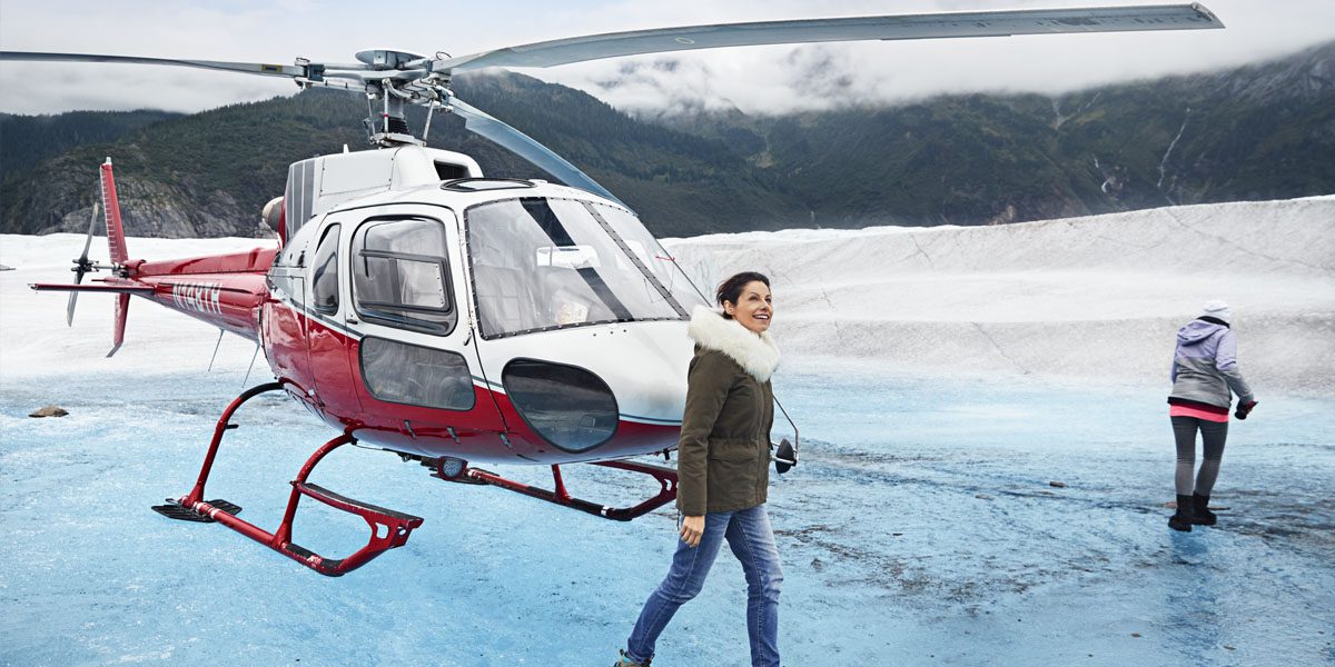 A woman walking in front of a helicopter.