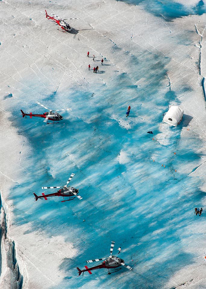 A helicopter flying over some people in the water.