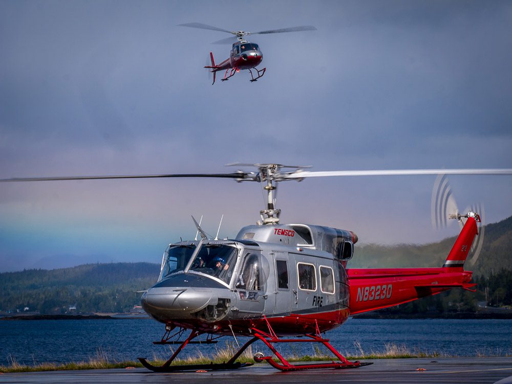 A helicopter is flying over the water and landing.