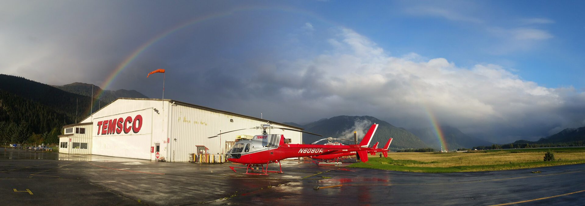 A red helicopter parked in front of a building.