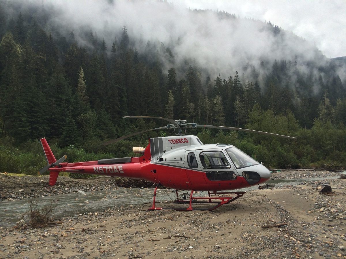 A red and white helicopter sitting on top of a dirt field.