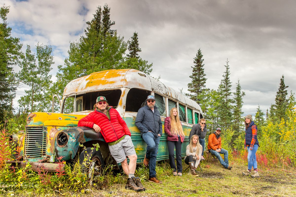 A group of people standing next to an old bus.