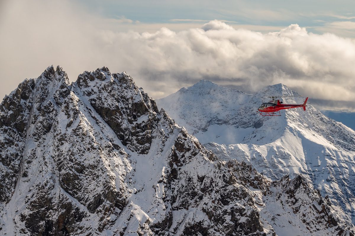 A helicopter flying over the mountains in winter.