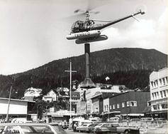 A helicopter is flying over the rooftops of some buildings.
