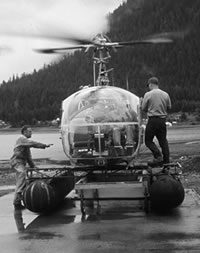 Two men working on a helicopter in the water.