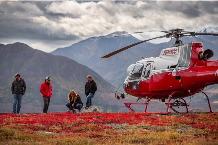 a group of people standing next to a helicopter